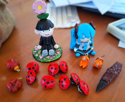 Air-dry clay figures, charms and pins painted with acrylics